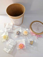 Fondants parfumés floraux Maison Mousse colorés, disposés devant le pot kraft