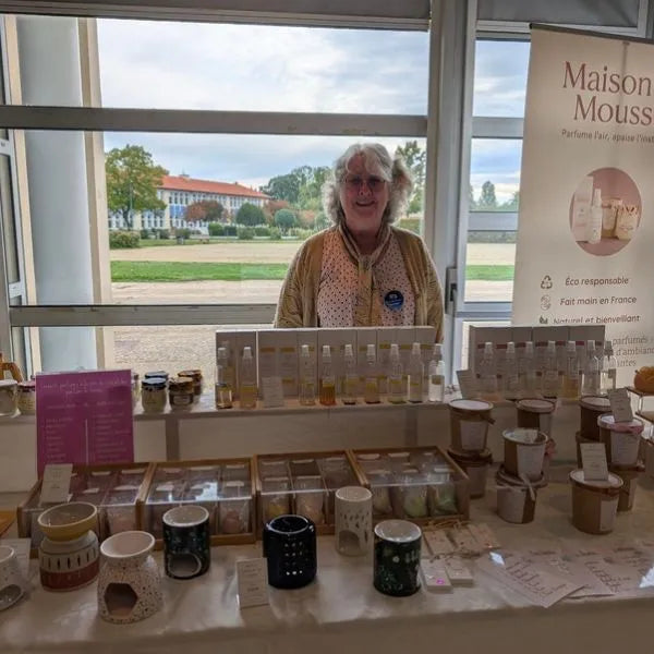 Sylvie, créatrice de Maison Mousse, derrière son stand sur un marché de créateurs pour présenter ses parfums d'ambiance